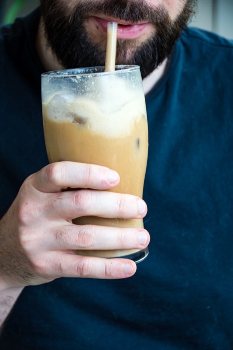 man holding a iced latte